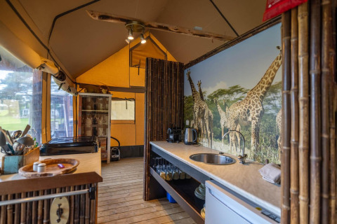 Interior de tienda safari decorada con bambú y mural de jirafas en Wilsumer Berge, Alemania.