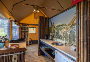 Interior de tienda safari decorada con bambú y mural de jirafas en Wilsumer Berge, Alemania.