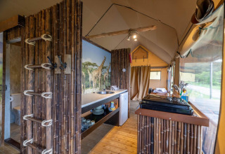 Interno di una tenda safari a Wilsumer Berge, Germania, con arredi in bambù e murale di giraffe.