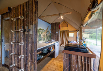 Interior de una tienda safari en Wilsumer Berge, Alemania, con decoración de bambú y mural de jirafas.