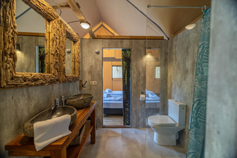 Baño moderno en tienda safari en Wilsumer Berge, Alemania, con lavabos de piedra y espejos rústicos.