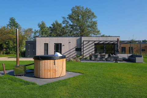 Villa de vacances Amalia 4 avec jacuzzi au Hofparken Wiltershaar, Pays-Bas, terrasse et pelouse visibles.