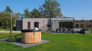 Villa de vacances Amalia 4 avec jacuzzi au Hofparken Wiltershaar, Pays-Bas, terrasse et pelouse visibles.