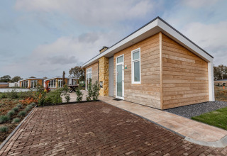 Lodge moderno de madera en el Resort Mooi Bemelen, Países Bajos, rodeado de senderos y paisaje ajardinado.