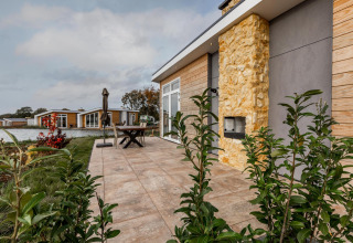 Terraza exterior en Lodge Biebosch, Resort Mooi Bemelen, Países Bajos, con vista al lago y casas modernas.