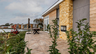 Terraza exterior en Lodge Biebosch, Resort Mooi Bemelen, Países Bajos, con vista al lago y casas modernas.
