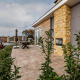 Patio at Lodge Biebosch, Resort Mooi Bemelen, Netherlands, with stone wall, plants, and modern lakeside lodges.