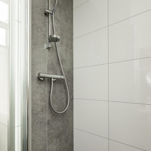 Ducha moderna en la cabaña Biebosch, Resort Mooi Bemelen, Países Bajos, con azulejos grises y blancos.
