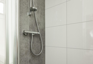 Ducha moderna en la cabaña Biebosch, Resort Mooi Bemelen, Países Bajos, con azulejos grises y blancos.