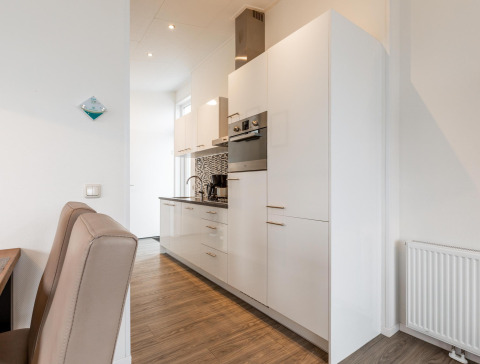 Cocina moderna blanca con armarios y electrodomésticos integrados en Biebosch, Resort Mooi Bemelen, Países Bajos.