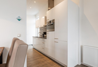 Cocina moderna blanca con armarios y electrodomésticos integrados en Biebosch, Resort Mooi Bemelen, Países Bajos.