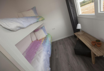 Habitación con literas, mesa de madera, lámpara y ventana en la cabaña Biebosch del Resort Mooi Bemelen, Países Bajos.