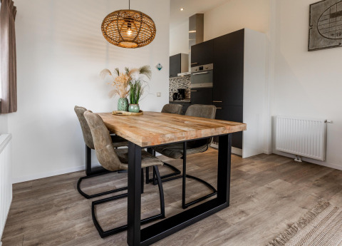 Comedor moderno con mesa de madera, cuatro sillas y lámpara colgante en una cabaña del Resort Mooi Bemelen, Países Bajos.