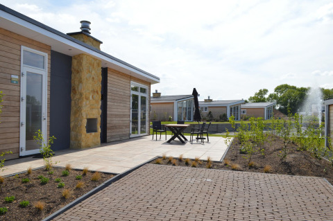 Terraza exterior de la moderna cabaña Biebosch en Resort Mooi Bemelen, Países Bajos, con mesas y sillas.