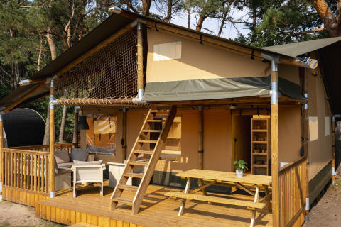 Tienda safari en Wilsumer Berge, Alemania, con terraza de madera, zona de estar exterior y entre árboles.