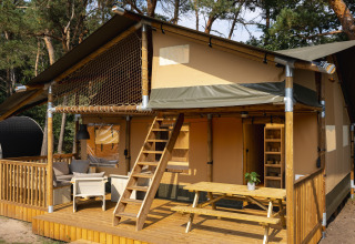 Tienda safari en Wilsumer Berge, Alemania, con terraza de madera, zona de estar exterior y entre árboles.
