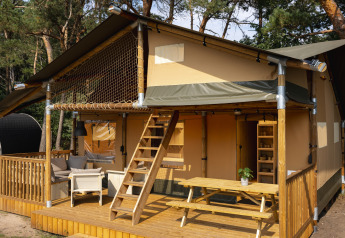 Tienda safari en Wilsumer Berge, Alemania, con terraza de madera, zona de estar exterior y entre árboles.
