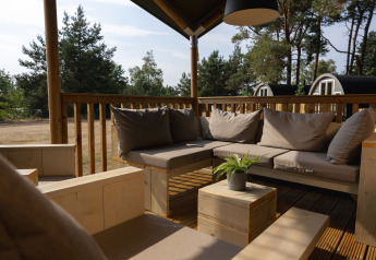 Zona de descanso exterior en una tienda safari en Wilsumer Berge, Alemania, con muebles de madera y cojines.