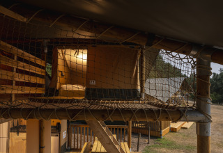 Binnenkant van een safaritent op Wilsumer Berge, Duitsland, met netten zolder en knusse slaapplek.