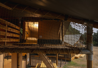 Interno di una tenda safari a Wilsumer Berge, Germania, con soppalco in rete e zona notte illuminata.