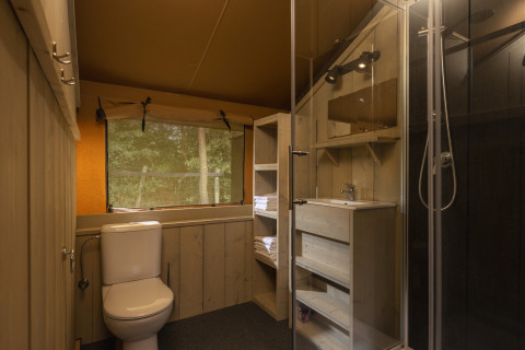 Baño en una tienda safari en Wilsumer Berge, Alemania, con ducha, inodoro y ventana al bosque.