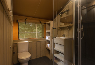 Baño en una tienda safari en Wilsumer Berge, Alemania, con ducha, inodoro y ventana al bosque.