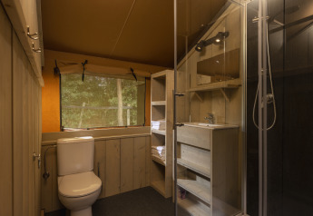 Baño en una tienda safari en Wilsumer Berge, Alemania, con ducha, inodoro y ventana al bosque.