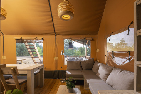 Vista interior de una tienda safari en Wilsumer Berge, Alemania, con sofás cómodos y mesa de comedor.