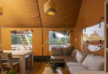 Vista interior de una tienda safari en Wilsumer Berge, Alemania, con sofás cómodos y mesa de comedor.