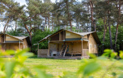 Tienda safari en Wilsumer Berge, Alemania, rodeada de árboles y naturaleza en un día soleado.