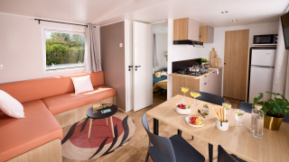 Moderne opholdsstue og køkken i en hytte på Domaine Seasonova Saâne et Mer i Frankrig med spisebord og sofa.