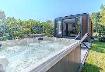 Vasca idromassaggio all'aperto e lettini vicino alla Forest Cabin presso Holiday Park BreeBronne, Paesi Bassi.