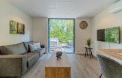 Modern living room in a Forest Cabin at Holiday Park BreeBronne, Netherlands, with terrace and forest view.