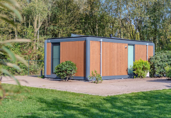 Cabane forestière au Holiday Park BreeBronne aux Pays-Bas entourée de verdure et d'arbres en été.