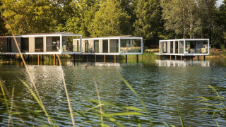 Lodges Water Cube sur pilotis au-dessus d’un lac paisible, entourés d’arbres verts et de nature.