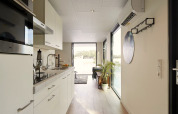 Cuisine moderne et couloir de la lodge Water Cube au Holiday Park BreeBronne, Pays-Bas, avec vue sur l’eau.