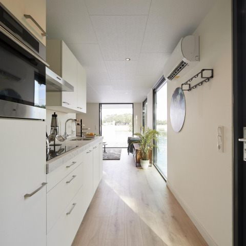 Moderne keuken en gang in de Water Cube-lodge bij Holiday Park BreeBronne, Nederland, met uitzicht op water.