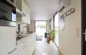 Cuisine moderne et couloir de la lodge Water Cube au Holiday Park BreeBronne, Pays-Bas, avec vue sur l’eau.