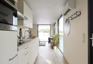 Moderne keuken en gang in de Water Cube-lodge bij Holiday Park BreeBronne, Nederland, met uitzicht op water.