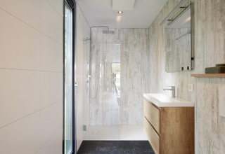 Moderne badkamer in de Water Cube lodge, Holiday Park BreeBronne, Nederland, met houten elementen en inloopdouche.