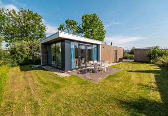 Lodge padiglione moderno con grandi finestre e zona pranzo esterna nel verde a Poort van Zeeland, Paesi Bassi.
