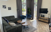 Sala moderna en el lodge Pavilion en Poort van Zeeland, Países Bajos, con sofá, sillones y grandes ventanas.