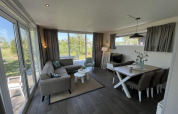 Helles, modernes Pavillon-Wohnzimmer mit Fenstern, Essbereich und Sofa im Poort van Zeeland, Niederlande.