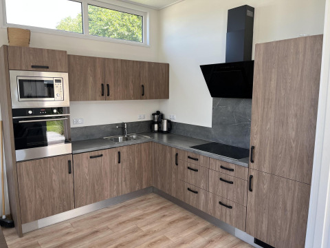 Cocina moderna en el Pabellón de Poort van Zeeland, Países Bajos, con gabinetes de madera y electrodomésticos.