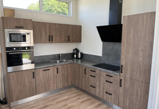 Cocina moderna en el Pabellón de Poort van Zeeland, Países Bajos, con gabinetes de madera y electrodomésticos.