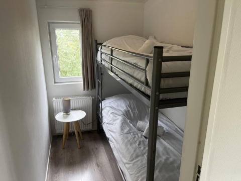 Kleines Schlafzimmer mit Etagenbett, Fenster, Nachttisch und Lampe im Pavilion bei Poort van Zeeland, Niederlande.