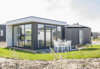 Pavillon moderne à Poort van Zeeland, Pays-Bas, avec grandes baies vitrées et coin repas extérieur.