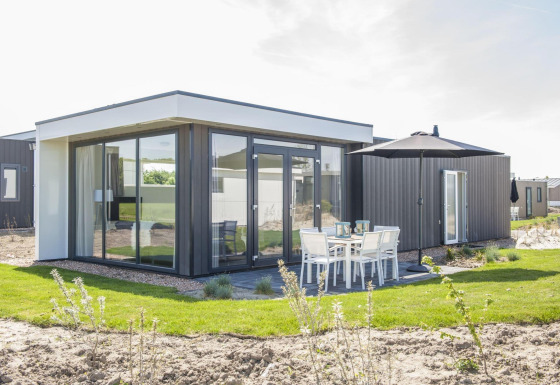 Pavillon moderne à Poort van Zeeland, Pays-Bas, avec grandes baies vitrées et coin repas extérieur.