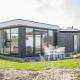Moderne lodge Pavilion bij Poort van Zeeland, Nederland, met grote ramen en buitenterras met tafel.