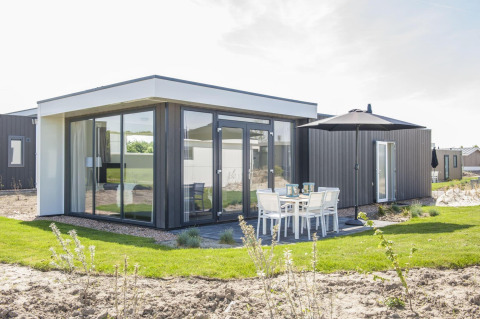 Moderne Pavilion-Lodge in Poort van Zeeland, Niederlande, mit Glasfront und Sitzbereich im Freien.